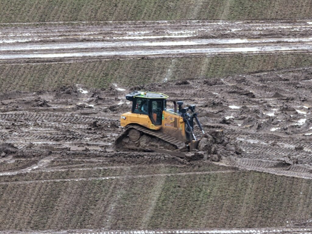 A bulldozer moves very wet mud